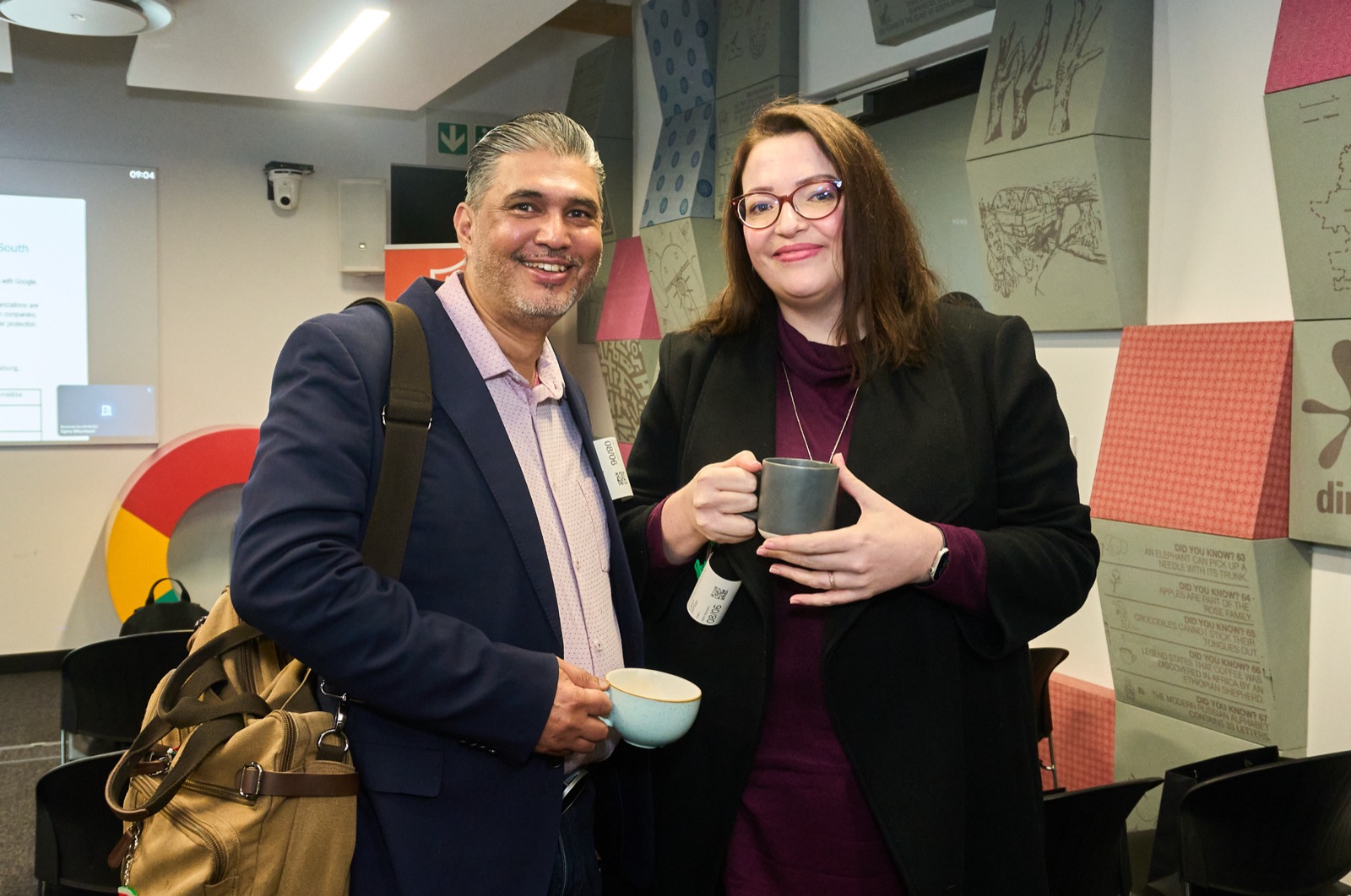 Two guests laughing over coffee between sessions